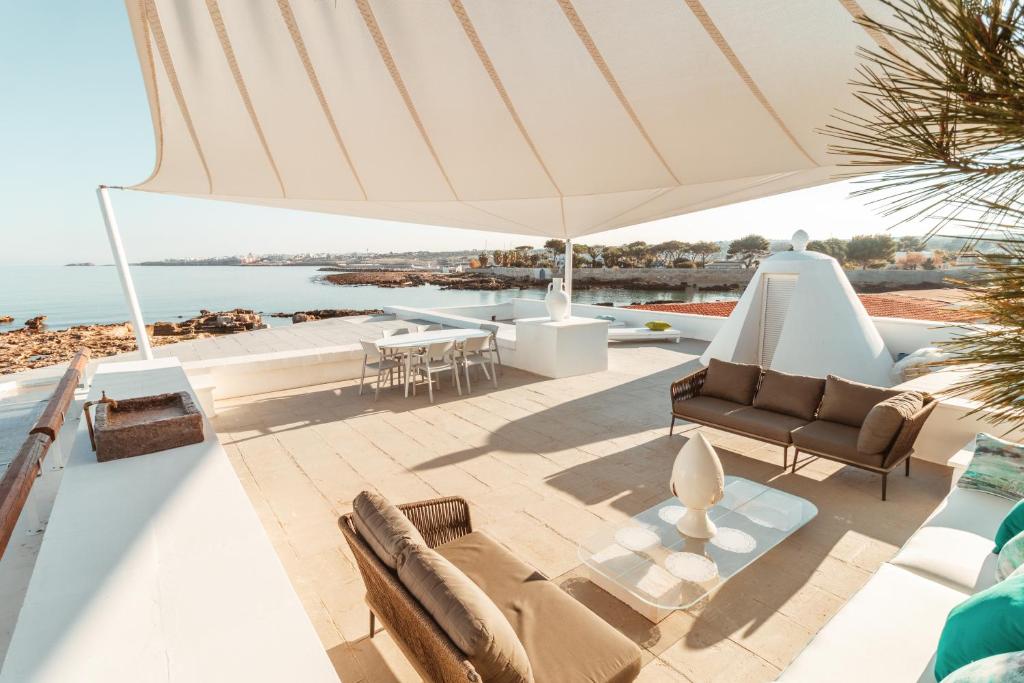 eine Terrasse mit Sofas und einem großen Sonnenschirm in der Unterkunft Echi di Puglia Marsento in Polignano a Mare