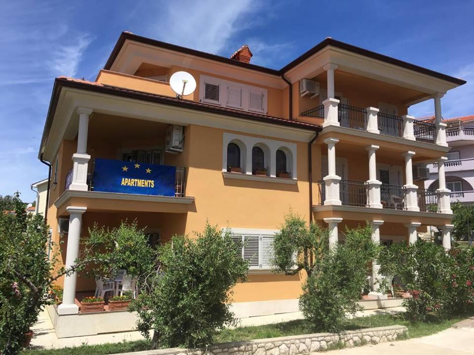 a large yellow building with a blue sign on it at Villa Dubravka in Lopar