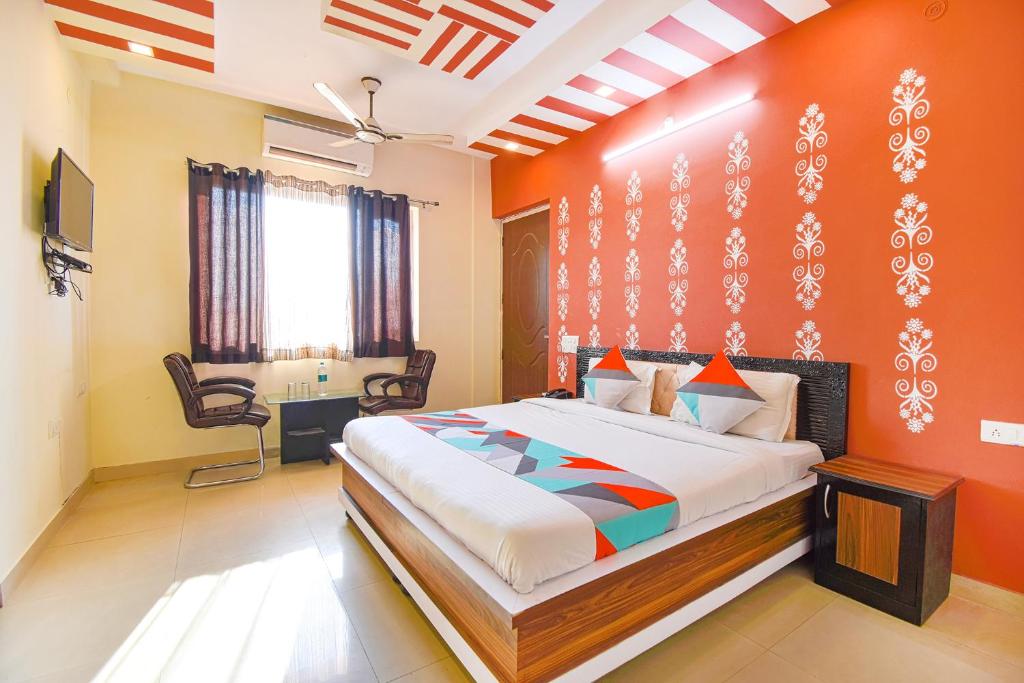 a bedroom with a bed with an orange wall at FabExpress Bzoie Heritage in Dehradun