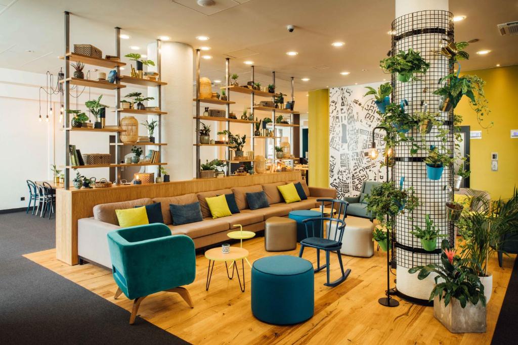 a living room filled with furniture and plants at Vienna House Easy by Wyndham Cracow in Kraków