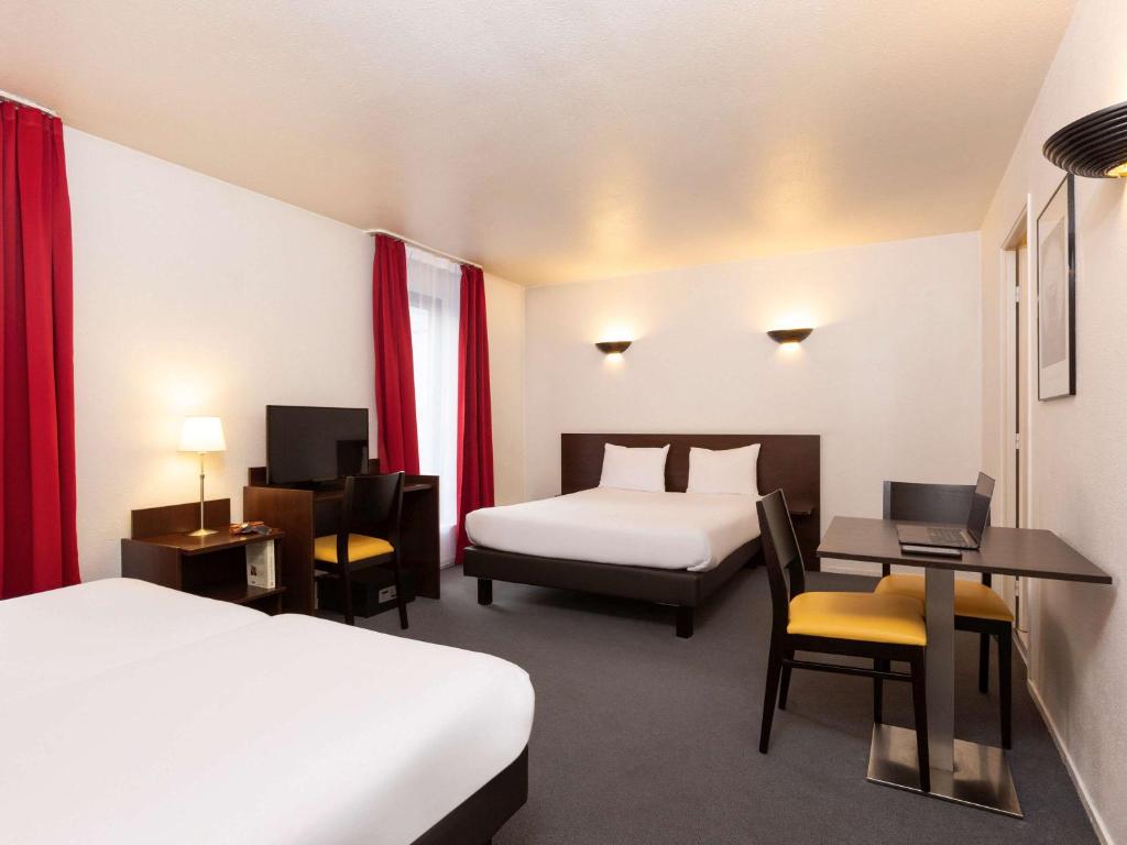 Cette chambre comprend deux lits, un bureau et une table. dans l'établissement Aparthotel Adagio Access La Défense - Léonard De Vinci, à Courbevoie
