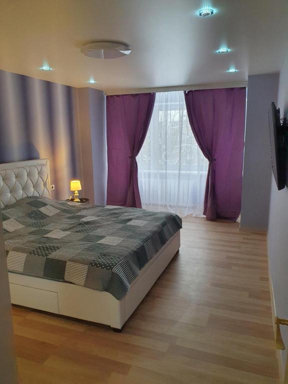 Schlafzimmer mit einem Bett und lila Vorhängen in der Unterkunft Kreenholm apartments in Narva