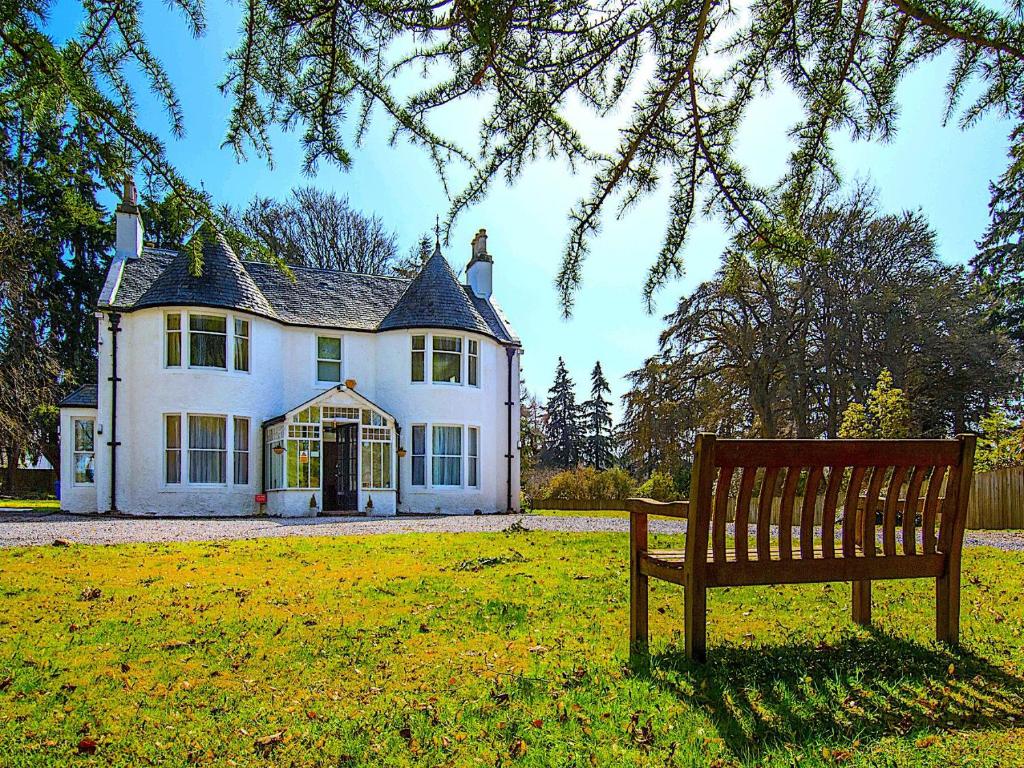 eine Bank, die vor einem weißen Haus sitzt in der Unterkunft Drumdevan Country House, Inverness in Inverness