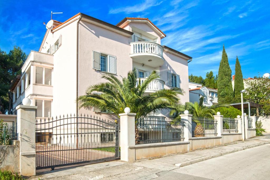 a white house with a fence and a palm tree at Apartments Ori in Pula
