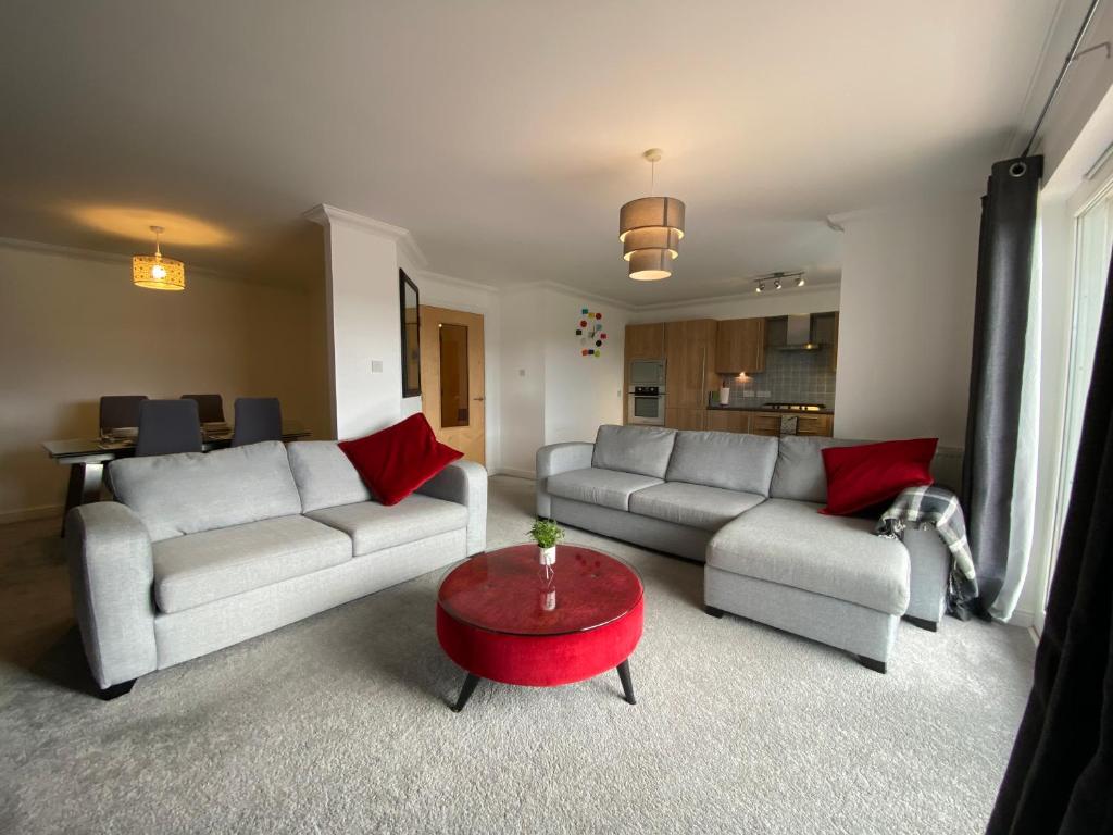 a living room with two couches and a red table at The Duplex Nairn- Spacious 3 Bedroom with sunny balcony in Nairn