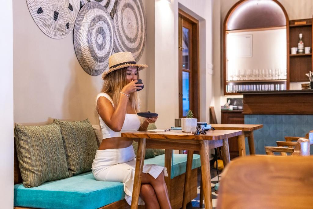a woman in a hat sitting at a table at The Merchant in Galle