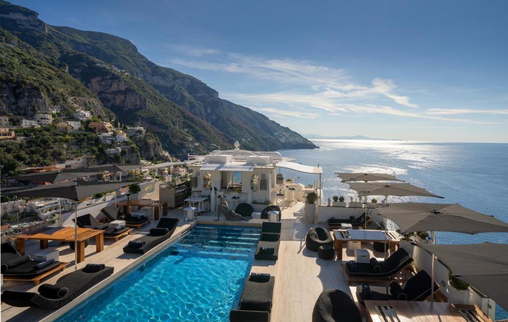 una piscina con sedie e ombrelloni accanto all'oceano di Hotel Villa Franca a Positano