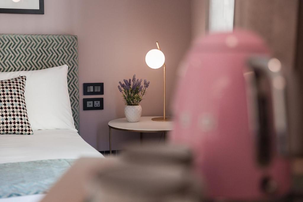 123 MAINSTREET boutique hotel في سانت جوليانز: غرفة نوم بسرير وطاولة مع مصباح