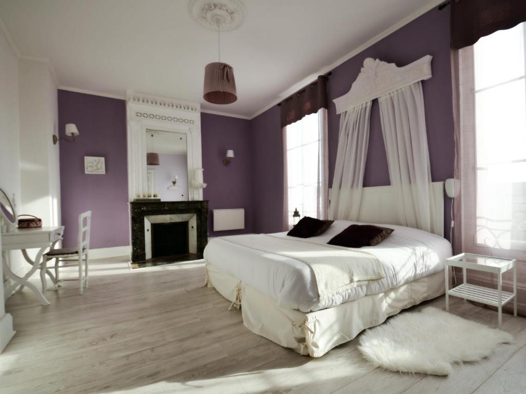 ein Schlafzimmer mit einem Bett mit lila Wänden und einem Kamin in der Unterkunft Le Petit Domaine de Colayrac in Colayrac-Saint-Cirq