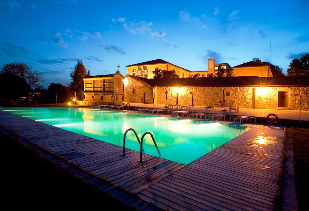 a swimming pool in front of a building at night at Hotel Pazo de Lestrove by Pousadas de Compostela in Padrón