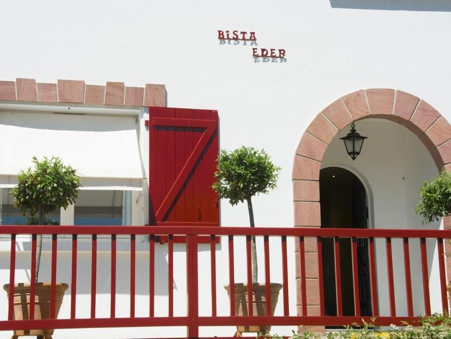 eine rote Tür auf einem Gebäude mit einem roten Zaun in der Unterkunft Maison Bista Eder in Bidart