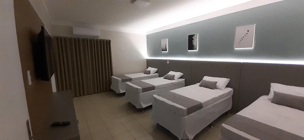 een kamer met drie bedden en een tv. bij Liv Hotel in Pôrto Ferreira