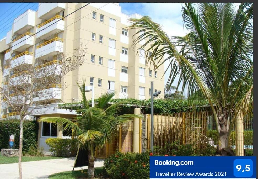 un grand bâtiment avec des palmiers devant lui dans l'établissement Apartamento - Jd São Lourenço - Bertioga - Praia da Riviera, à Bertioga