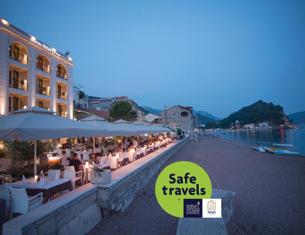 a restaurant with tables and umbrellas next to the water at Hotel Riva by Aycon in Petrovac na Moru