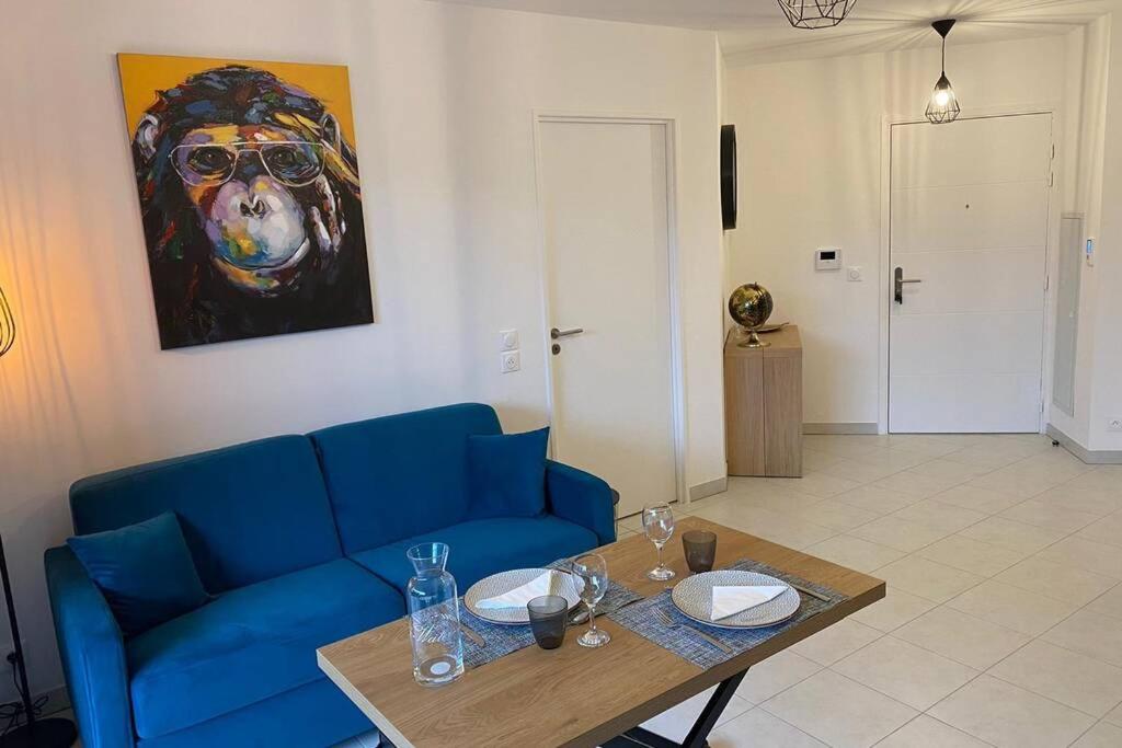 uma sala de estar com um sofá azul e uma mesa em Deux pieces Moderne et Chaleureux em Saint-Laurent-du-Var