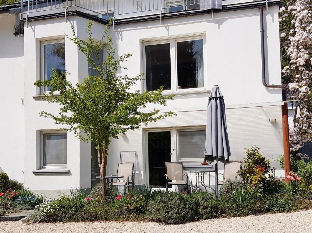 a white house with an umbrella and chairs at Ferienwohnung Granzow in Gaienhofen