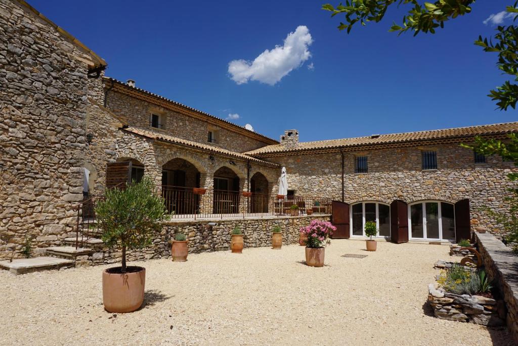 a large stone building with a courtyard with potted plants at La Buisse in Simiane-la-Rotonde