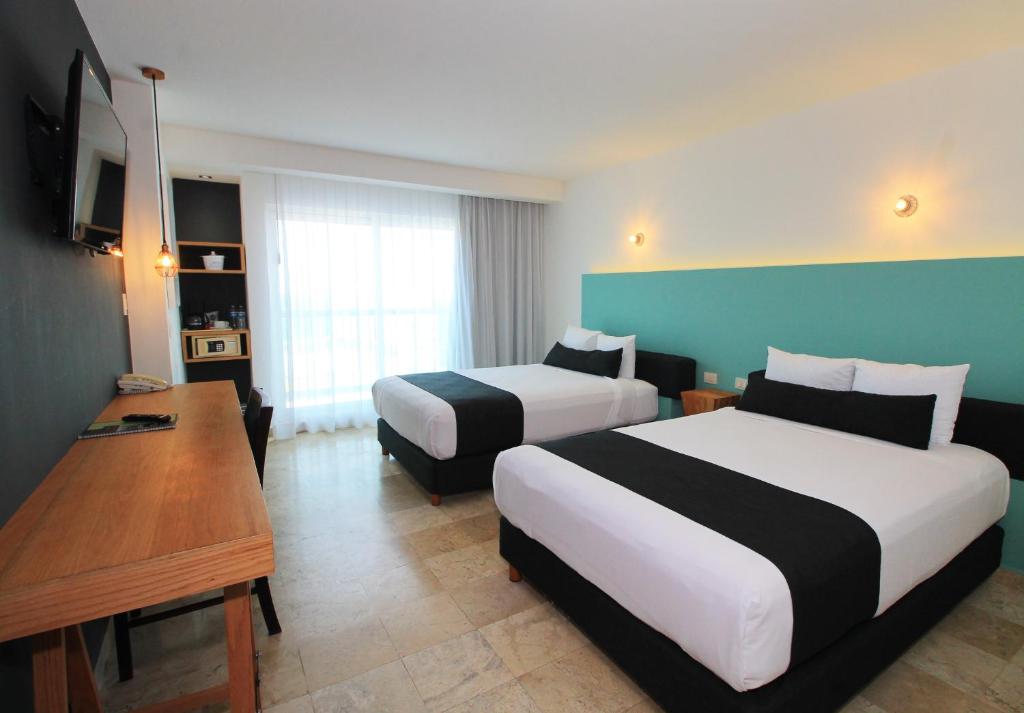 a hotel room with two beds and a desk at Rivoli Select Hotel in Veracruz