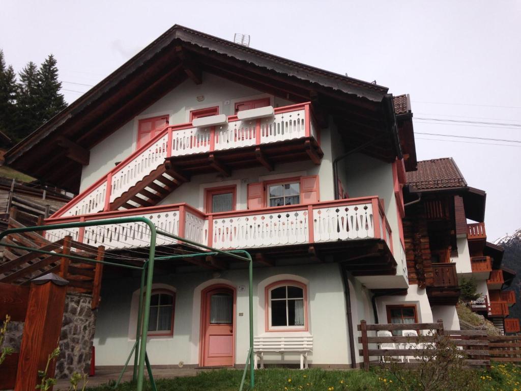 Casa con puertas rojas y balcón. en Appartamento Col Val di Fassa con giardino BAGNI RINNOVATI 2023, en Campitello di Fassa