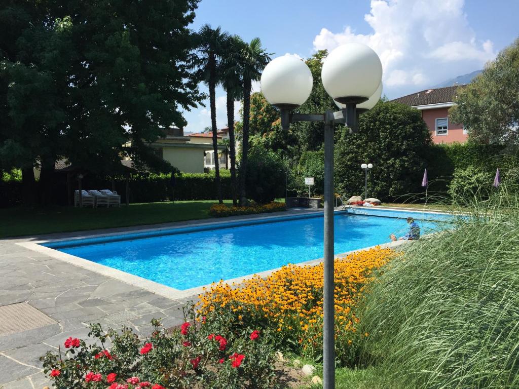 a light pole next to a swimming pool with flowers at Ascona: Sabrina Apt. 237 in Ascona