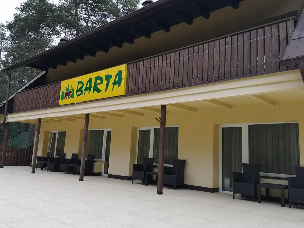 a restaurant with chairs and a sign on a building at Ośrodek Wypoczynkowy BARTA in Tylicz