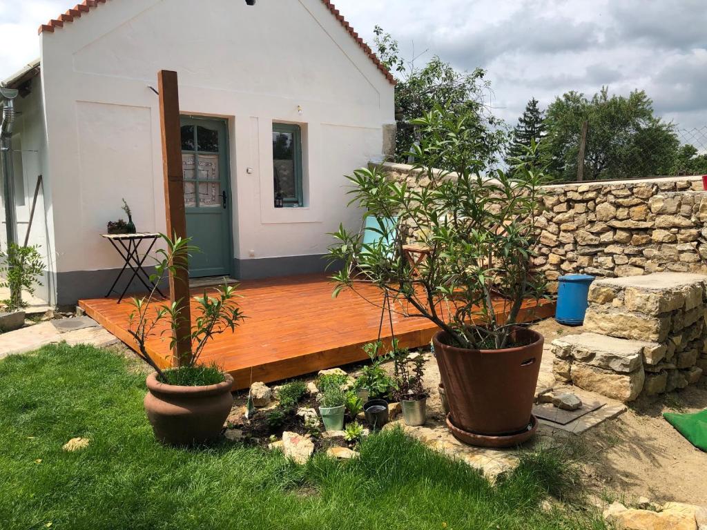 una terraza de madera con 2 macetas frente a un edificio en Káli Kerted Vendégházak Monoszló Mariska néni háza en Monoszló