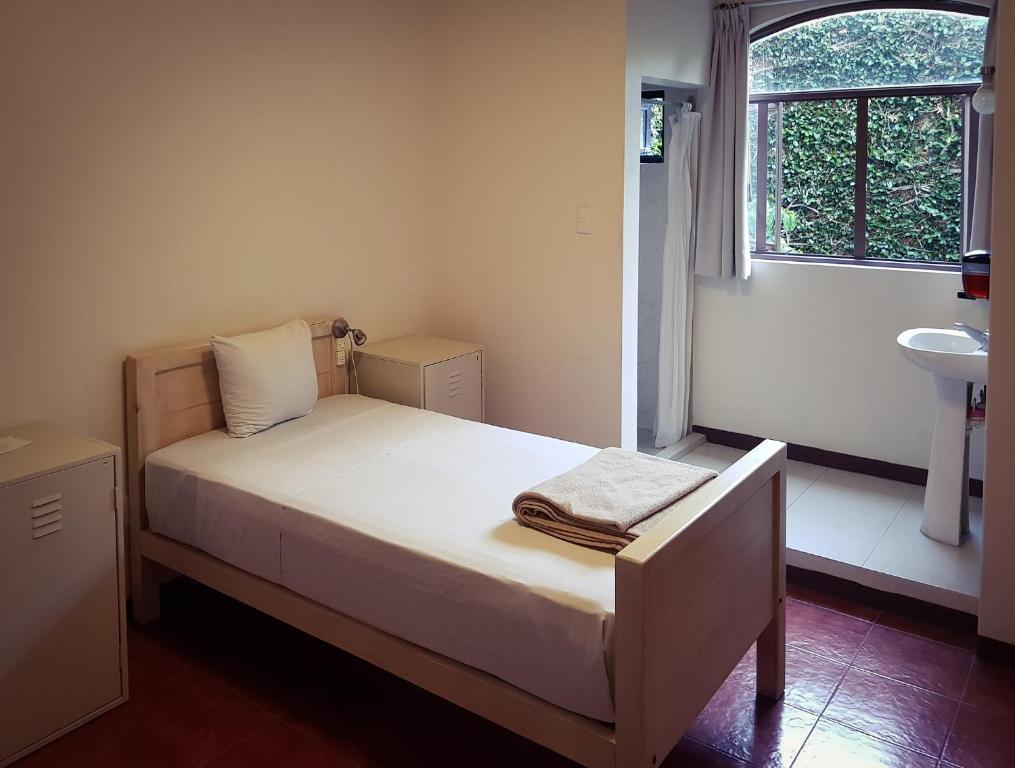 a white bed sitting in a bedroom next to a window at Hostal de Las Américas in Oaxaca City