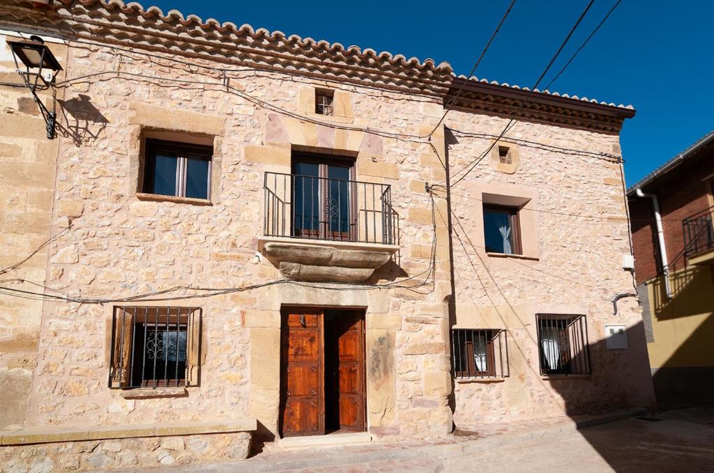 un antiguo edificio de piedra con puerta y balcón en La Casa El Cura, en Campillo de Dueñas