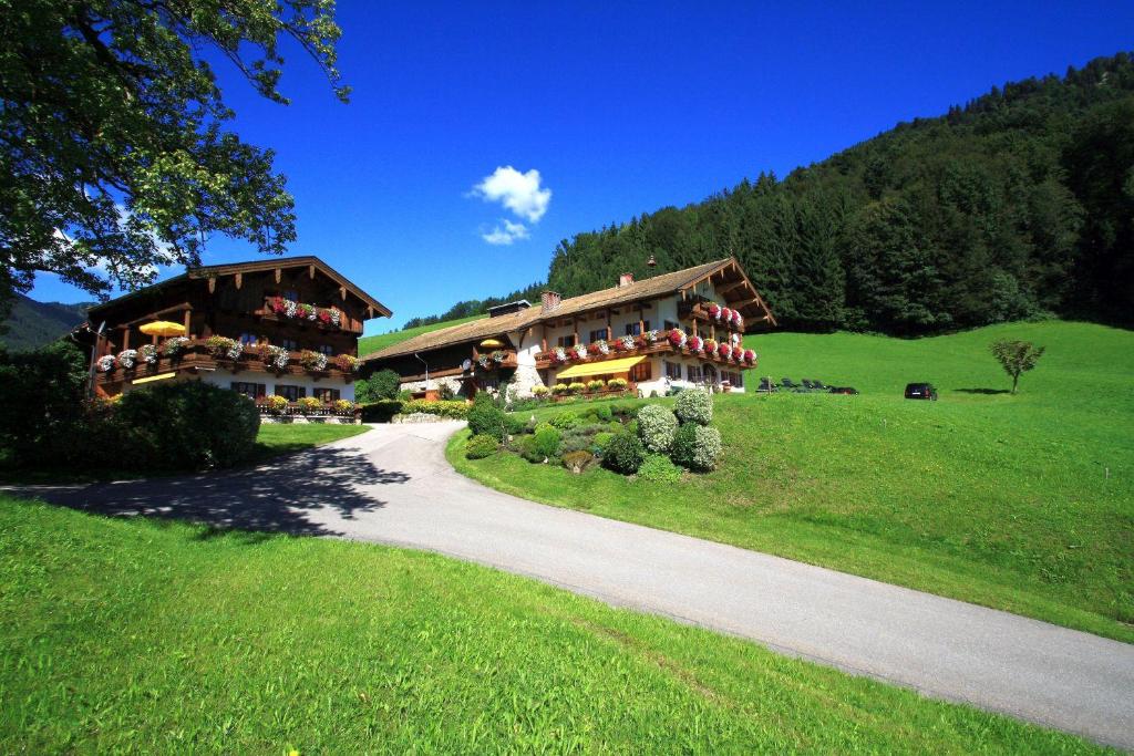 a large building on a green hill with a road at Obersteinberg-Hof in Ruhpolding