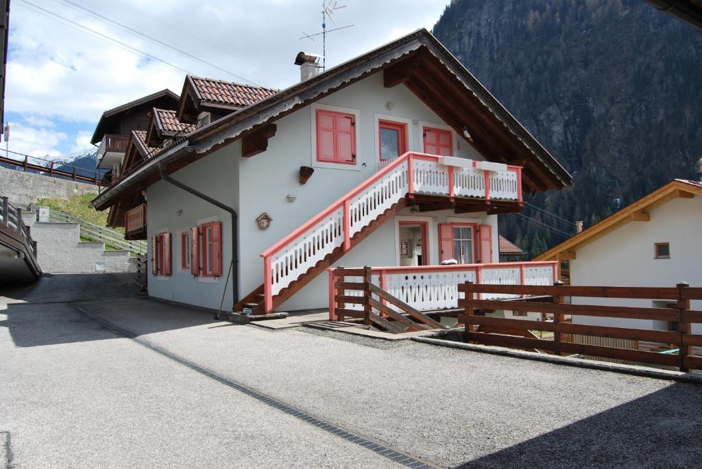 ein weißes Haus mit roten Fenstern und einem Zaun in der Unterkunft Appartamento Col Val di Fassa con Terrazza BAGNI RINNOVATI 2023 in Campitello di Fassa