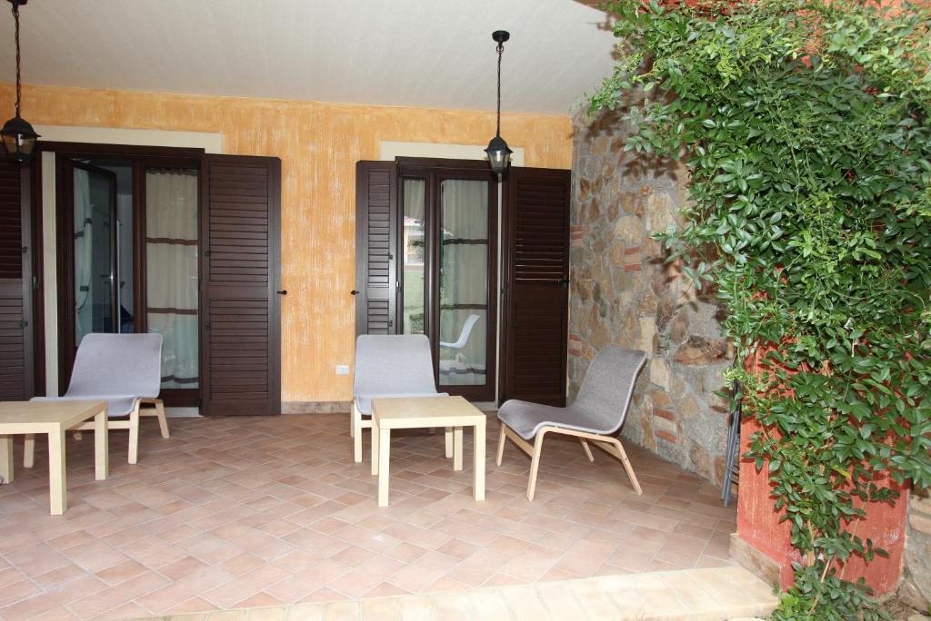 a patio with chairs and tables next to a wall at B&B Acquamarina Villasimius in Villasimius