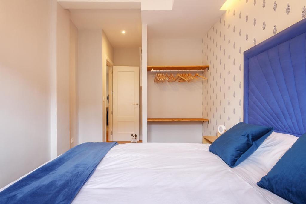 1 dormitorio con 1 cama grande y cabecero azul en Old bilbao Con Vistas a la Ria by Urban Hosts, en Bilbao