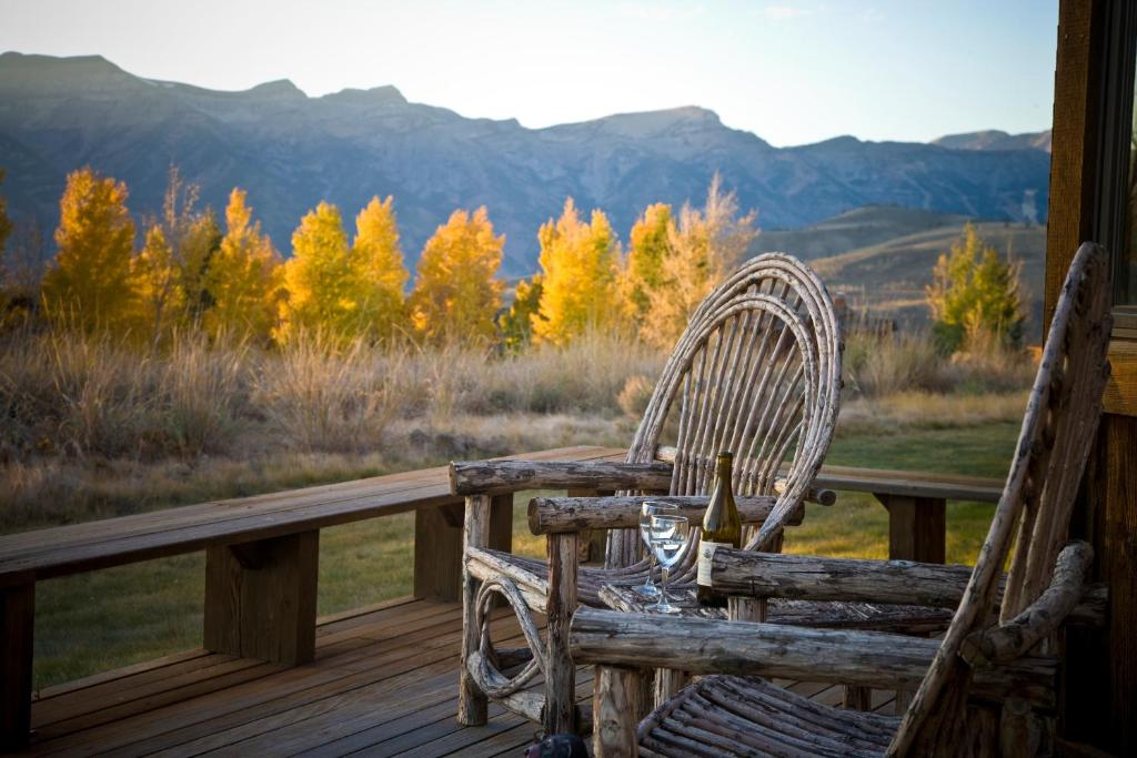 une chaise en bois sur une terrasse couverte avec un verre de vin dans l'établissement Spring Creek Ranch, à Jackson