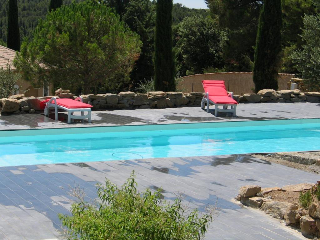 two red chairs sitting next to a swimming pool at Les Romarins in Aigne