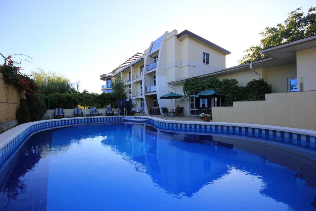 una piscina azul frente a un edificio en Guest House Lastochkino Gnezdo, en Krinitsa