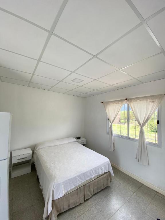 a white bedroom with a bed and a window at Departamento en La Punta in La Punta