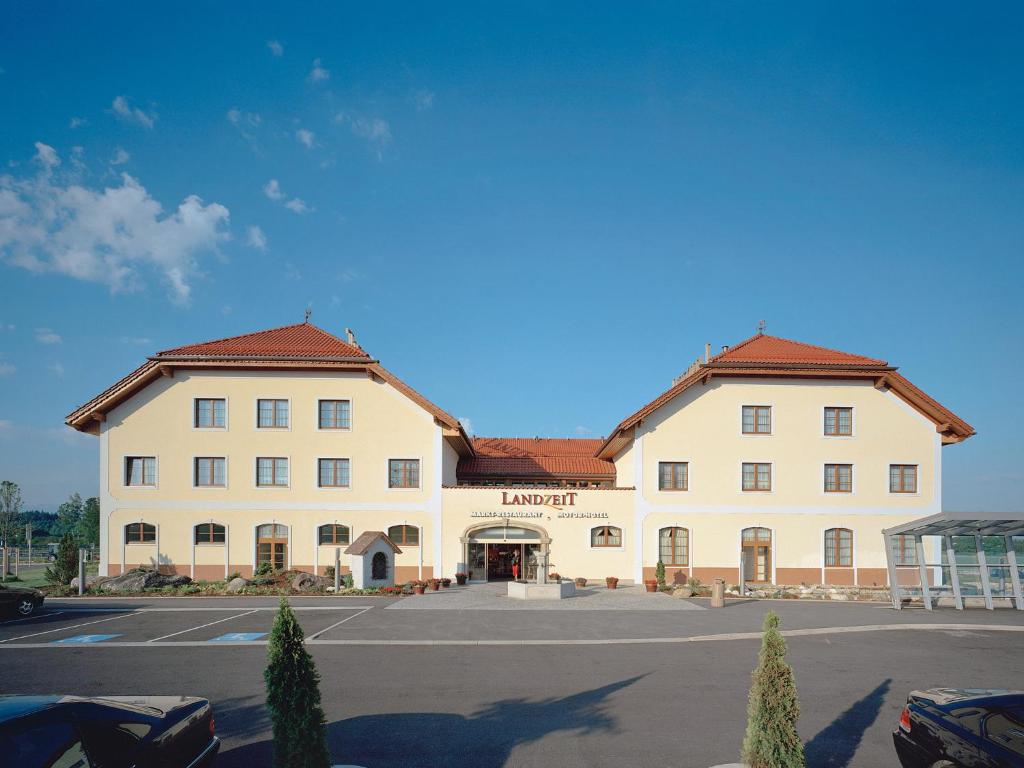 ein großes weißes Gebäude auf einem Parkplatz in der Unterkunft Landzeit Restaurant Voralpenkreuz in Sattledt