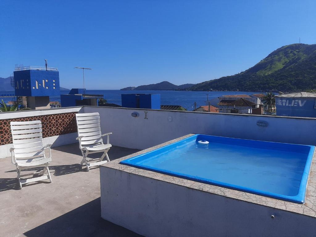 a swimming pool on the roof of a building with chairs at casa de praia ibicui in Mangaratiba
