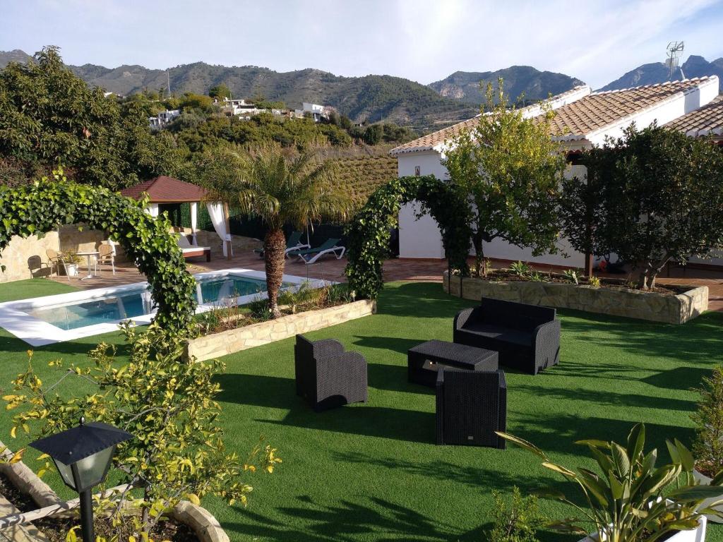 a garden with chairs and a swimming pool at Belvilla by OYO Cortijo Albaricoque in Frigiliana