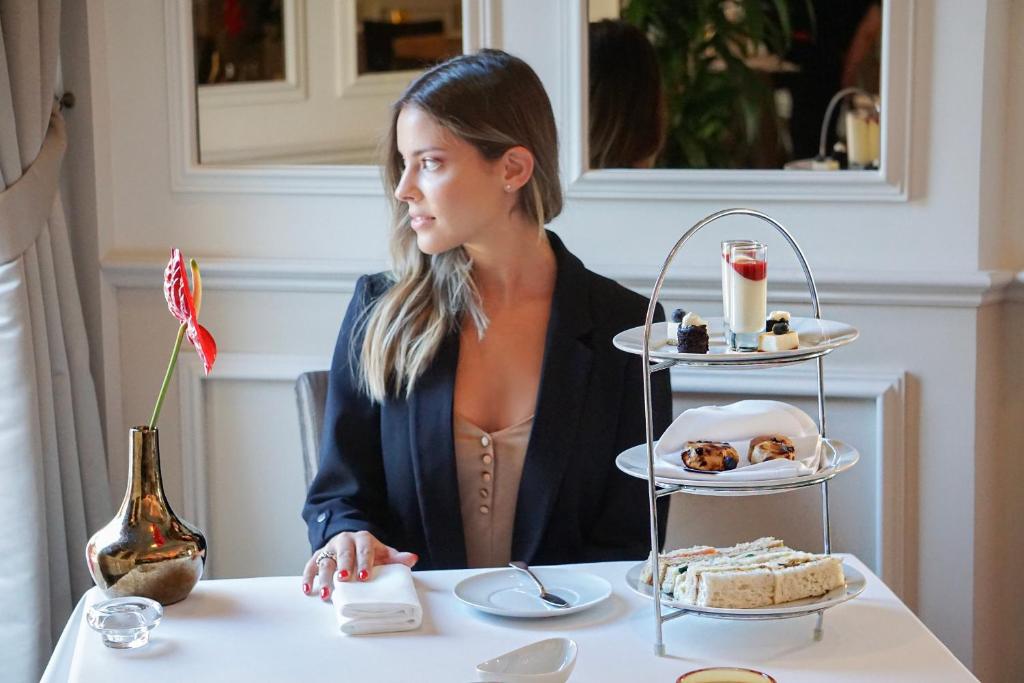 a woman sitting at a table with a plate of food at InterContinental Porto - Palacio das Cardosas by IHG in Porto