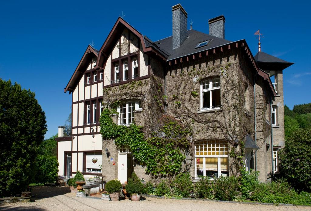 een groot stenen gebouw met een zwart dak bij Hotel La Ferronniere in Bouillon