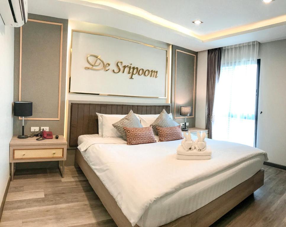 a bedroom with a large white bed with a sign on the wall at Hotel De Sripoom -SHA Extra Plus in Chiang Mai
