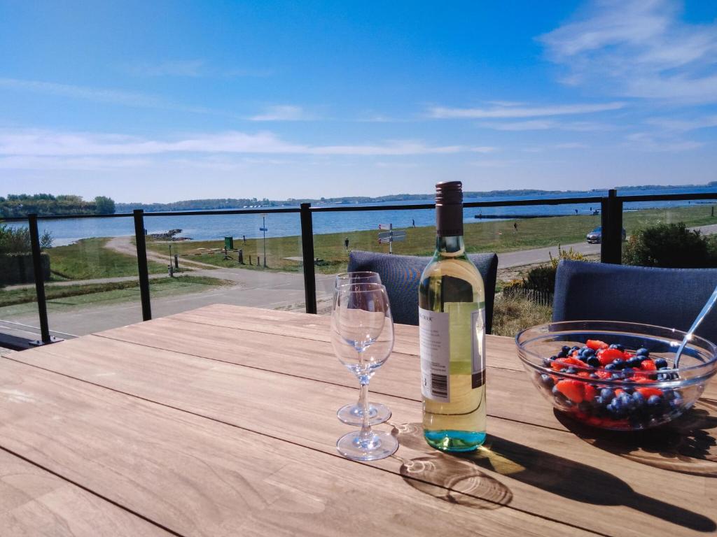 eine Flasche Wein auf einem Tisch mit einer Schale Obst in der Unterkunft Elegant Holiday Home in Kamperland next to the Lake in Kamperland
