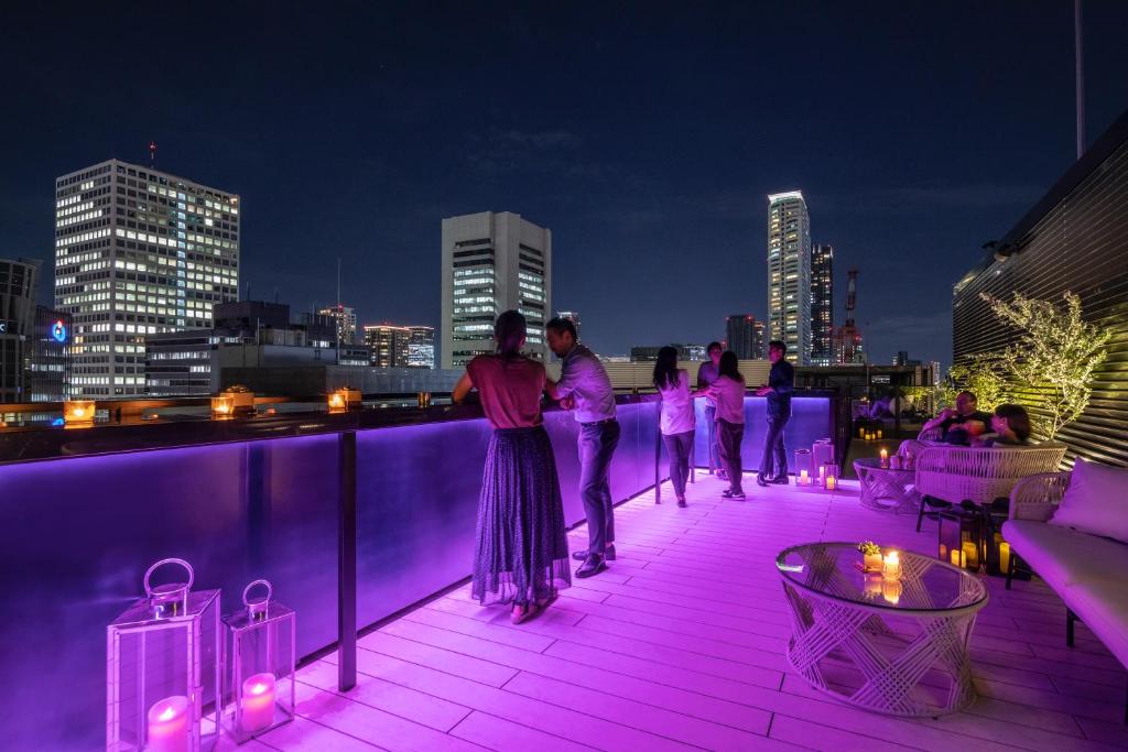 大阪市にあるTHE LIVELY 大阪本町の紫色の灯りを持つ屋上に立つ人々