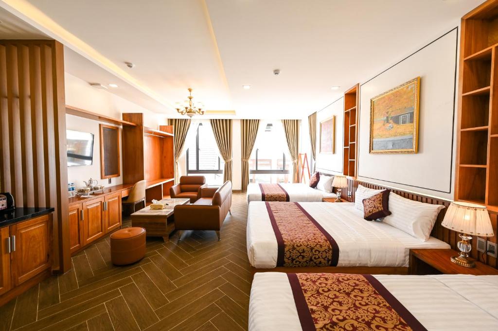 ダラットにあるLa Fleur Premium Central Apartment Hotelのベッド3台とリビングルームが備わるホテルルームです。
