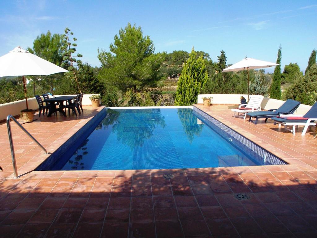 a swimming pool with chairs and a table and an umbrella at Belvilla by OYO Casa Lourdes in Sant Miquel de Balansat