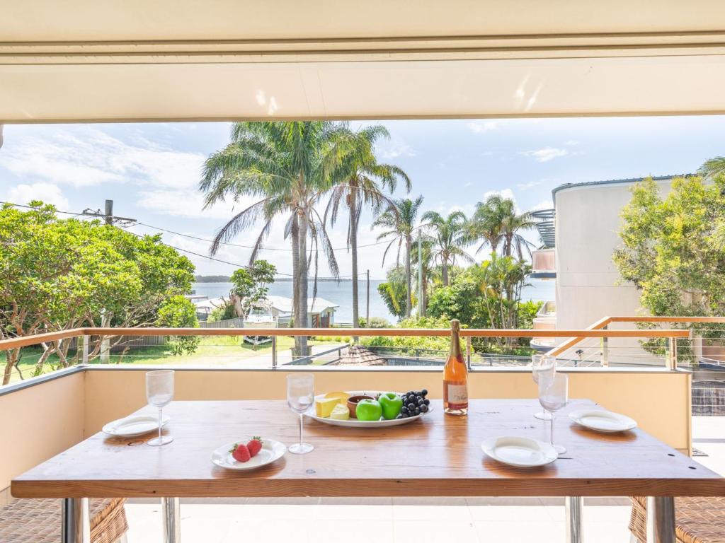 a table with a bowl of fruit and wine glasses at 1 Soldiers Point Road fabulous home with water views in Soldiers Point