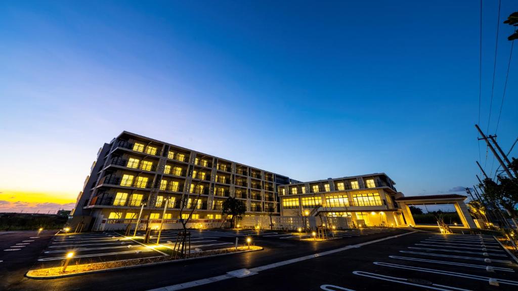 a large building with lights in a parking lot at Hotel Torifito Miyakojima Resort in Miyako-jima