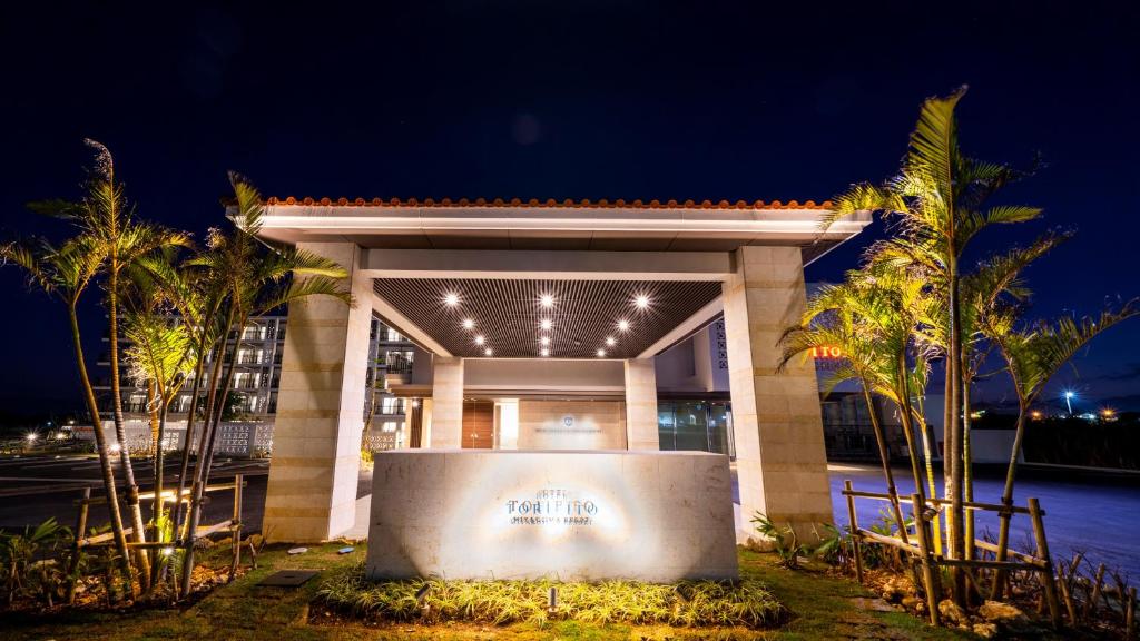 a building with palm trees in front of it at night at Hotel Torifito Miyakojima Resort in Miyako-jima