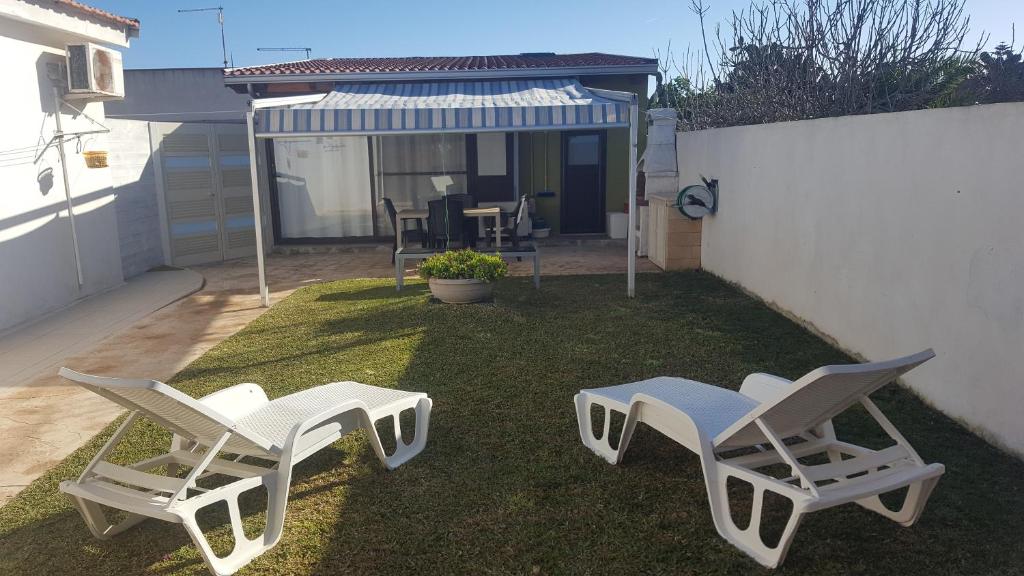 2 chaises blanches et une table dans la cour dans l'établissement Villa Marzamemi Beach, à Marzamemi